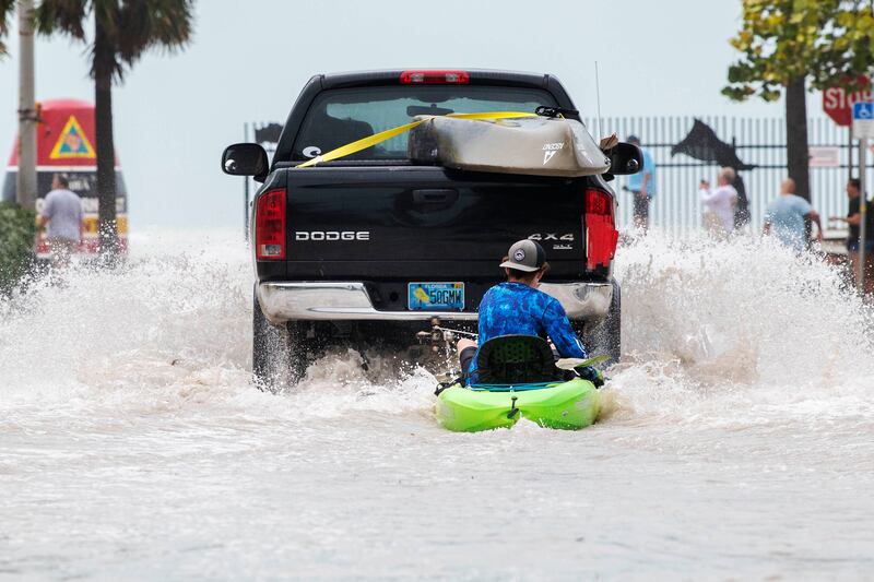 A pickup truck pulls a man on a kayak on a low-lying road after flooding in aftermath of Hurricane Ian, in Key West, Florida. AP