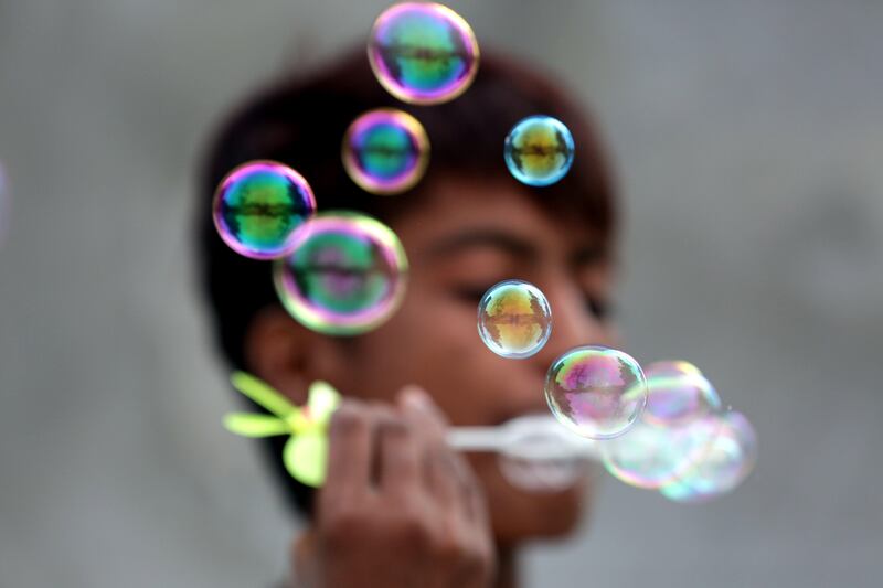 An Indian vendor blows bubbles from a bubble wand to attract customers at his roadside stall in Amritsar, India. RAMINDER PAL SINGH / EPA