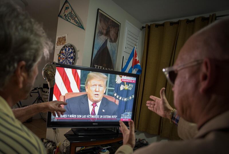 Miguel Saavedra and his friend Oswaldo Hernandez watch Donald Trump on TV, from their home in Miami. EPA
