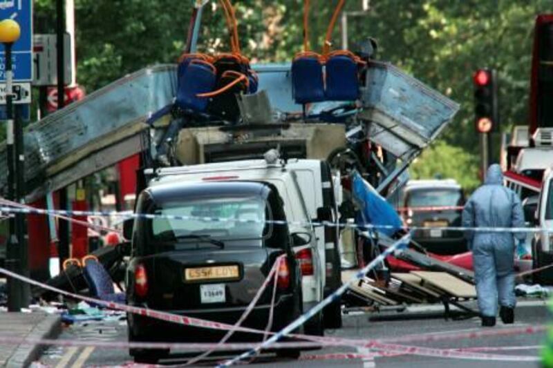 FILE -  In this July 7, 2005 file photo, a forensic officer walks next to the wreckage of a double decker bus with its top blown off and damaged cars scattered on the road at Tavistock Square in central London. European security officials said Wednesday Sept. 29, 2010, a terror plot to wage Mumbai-style shooting sprees or other low-budget attacks in Britain, France and Germany is still active and that sites in Pakistan _ where the threat was intercepted _ are being targeted for al-Qaida operatives. (AP Photo/Sang Tan, File)