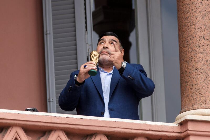 BUENOS AIRES, ARGENTINA - DECEMBER 26: Former Argentinian legend and current coach of Gimnasia y Esgrima La Plata Diego Maradona gestures with a small replica of the FIFA World Cup trophy at the balcony of Government house after a meeting with President of Argentina Alberto Fernandez at Casa Rosada on December 26, 2019 in Buenos Aires, Argentina. (Photo by Ricardo Ceppi/Getty Images)