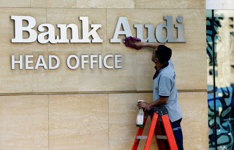 A worker cleans the logo of Bank Audi in Beirut. It is one of the largest lenders in Lebanon. Reuters