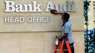 A worker cleans the logo of Bank Audi in Beirut. It is one of the largest lenders in Lebanon. Reuters