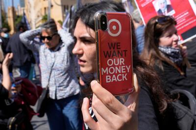 A protester displays her phone with a sticker saying 'we want our money back' at a demonstration outside a Beirut bank in May 2023. AP Photo
