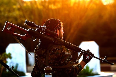 A Syrian Democratic Forces'(SDF) fighter holds a sniper rifle on his shoulder as he attends the funeral of a slain People's Protection Units (YPG) commander in the northeastern city of Qamishli on December 6, 2018.  / AFP / Delil SOULEIMAN
