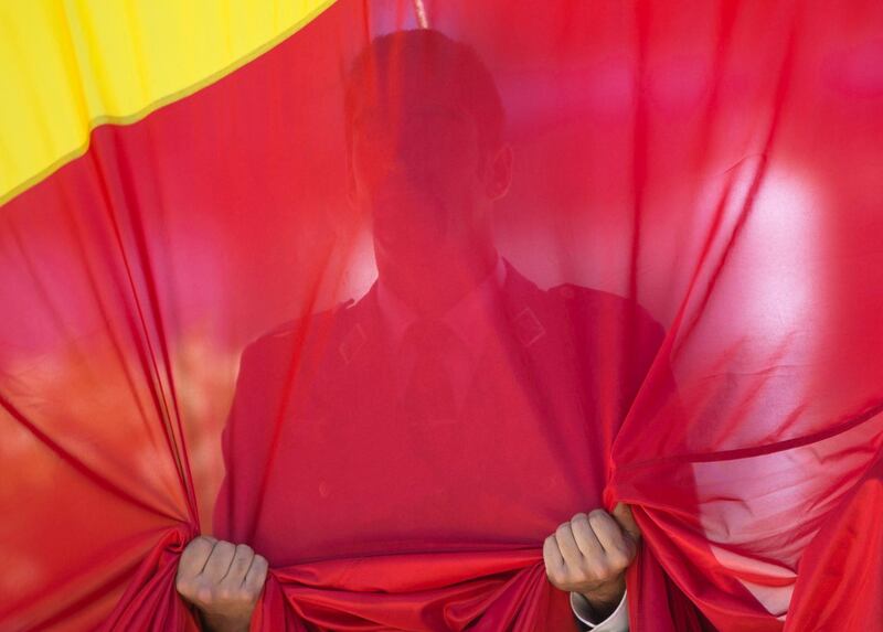 A soldier clutches part of a giant Spanish flag during the flag-raising ceremony celebrating the fourth anniversary of the proclamation of Spain's King Felipe VI at the Colon Plaza in Madrid. Paul White / AP Photo