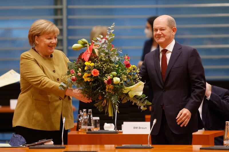 Mrs Merkel receives a bouquet of flowers from Olaf Scholz as she arrives for probably her last weekly cabinet meeting on November 24. Getty Images