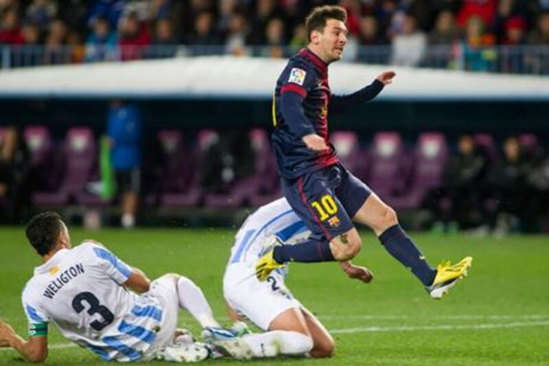 Barcelona's Lionel Messi avoids Malaga's Weligton de Oliveira to have a shot at goal.