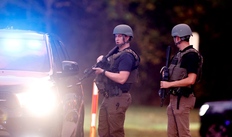 Law enforcement stand at the entrance to Neuse River Greenway Trail parking area after the shooting. AP