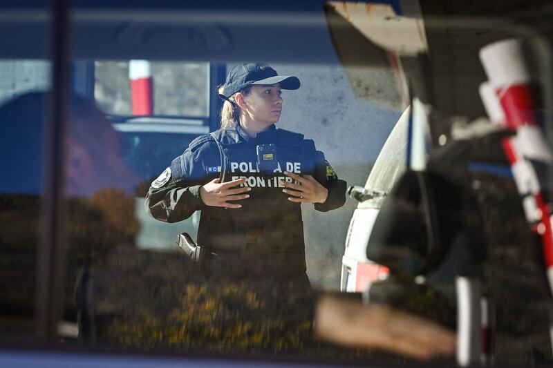 A Romanian border police officer inspects a car at the Serbian border checkpoint. AFP
