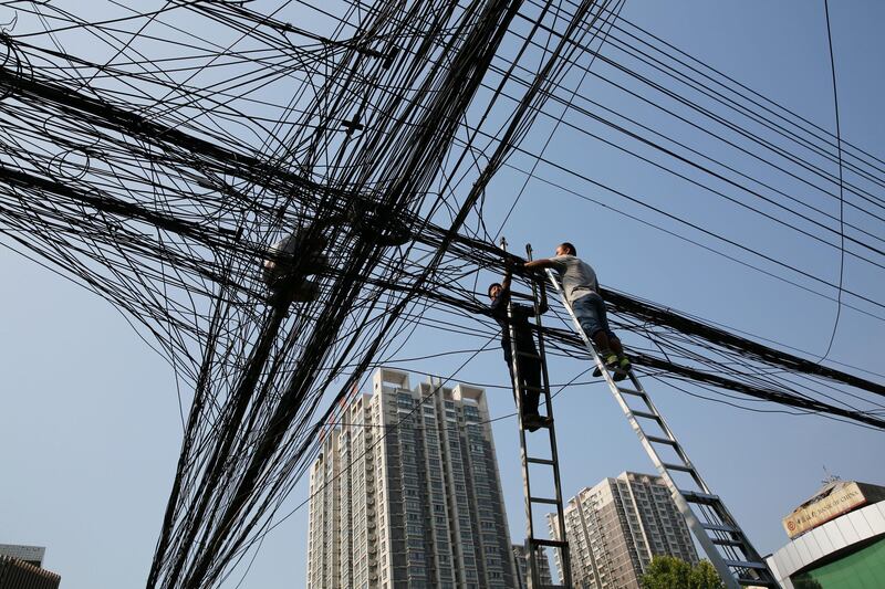 Workers work on overhead optical cables in Xi'an, Shanxi province, China. Reuters