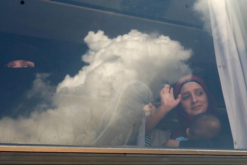 Syrian refugees wave through the windows of a bus as it leaves Beirut. AFP