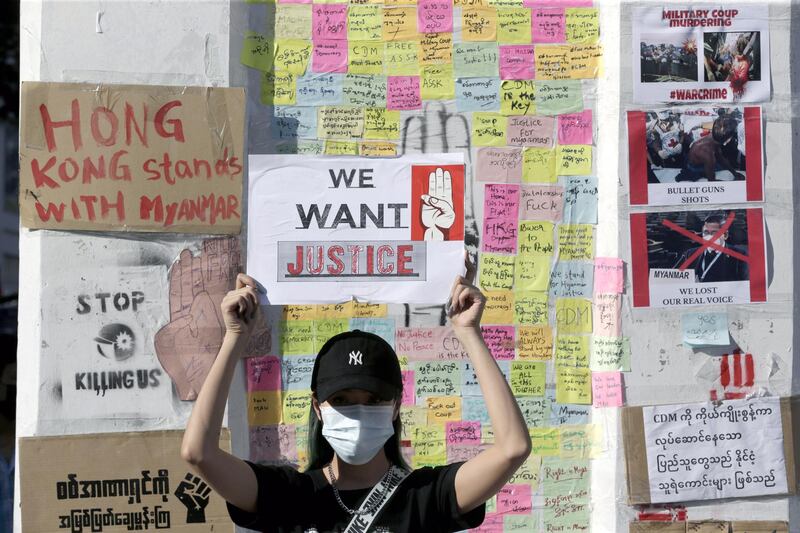 A demonstrator holds up a placard while standing in front of a wall of post-it notes and posters with messages protesting the military coup in Yangon. EPA