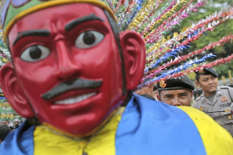 An Indonesian police officer peeks from behind a giant traditional puppet called “ondel-ondel” as he watches over a small protest outside City Hall in Jakarta, Indonesia, 2014. Dita Alangkara / AP 