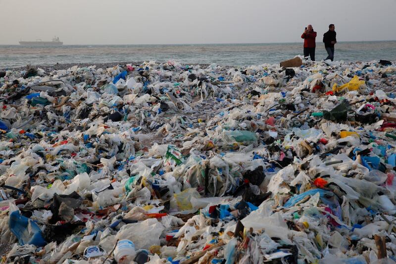 In this Monday, Jan. 22, 2018, photo, a man takes photos of piles of garbage washed on shore after an extended storm battered the Mediterranean country at the Zouq Mosbeh costal town, north of Beirut, Lebanon. Environmentalists say a winter storm has pushed a wave of trash onto the Lebanese shore outside Beirut, stirring outrage over a waste management crisis that has choked the country since 2015. (AP Photo/Hussein Malla)