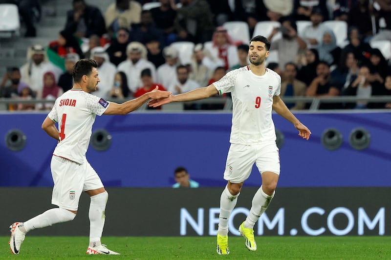 Iran's Mehdi Taremi, right, is congratulated by teammate Shojae Khalilzadeh after scoring their first goal. AFP