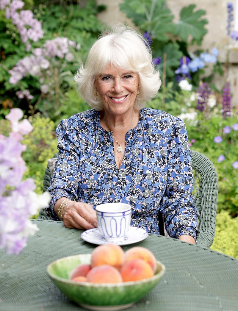 The queen consort, wearing a blue floral dress from Sophie Dundas, poses for an official portrait to mark her 75th birthday, at her home in Wiltshire, England. AP