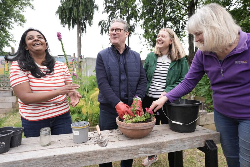 Mr Starmer helps volunteers pot plants during a visit to Harlesden Town Garden in north-west London. PA