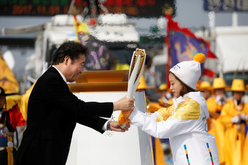 South Korean prime minister Lee Nak-yeon hands the Olympic torch to figure skating prospect and the first torchbearer of the country You Young on the Incheon bridge in Incheon, South Korea. Kim Hong-ji / Reuters