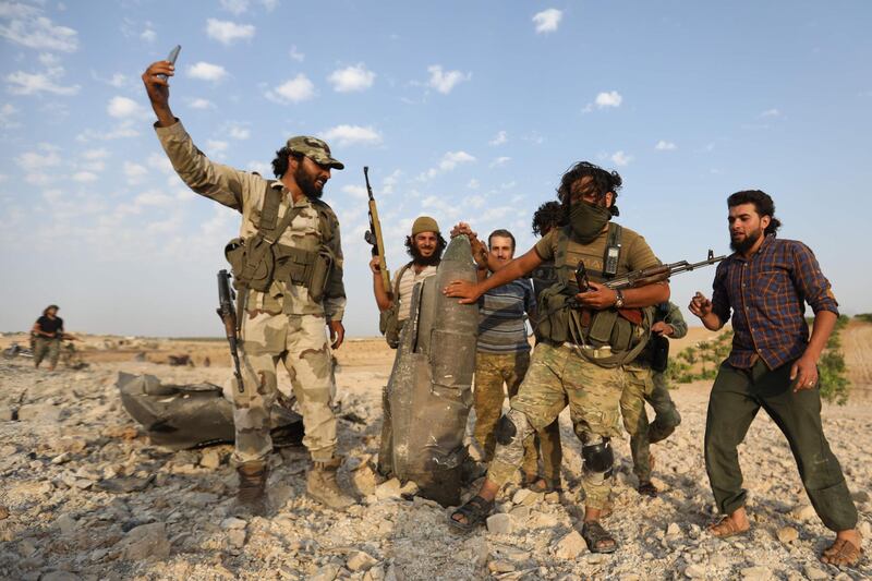 Rebel fighters pose for a picture with the remains of a downed regime warplane near the militant-held town of Khan Sheikhun in south Idlib province. AFP