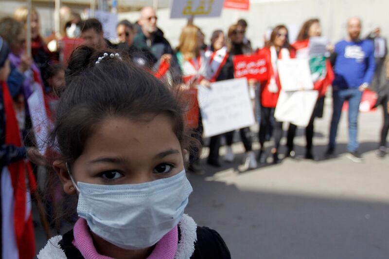 A girl wears a mask as anti-government protesters carry banners and shout slogans during a protest in front of the Lebanese Ministry of Health under the slogan 'Our life is not a toy in your hands' in Beirut, Lebanon.  EPA