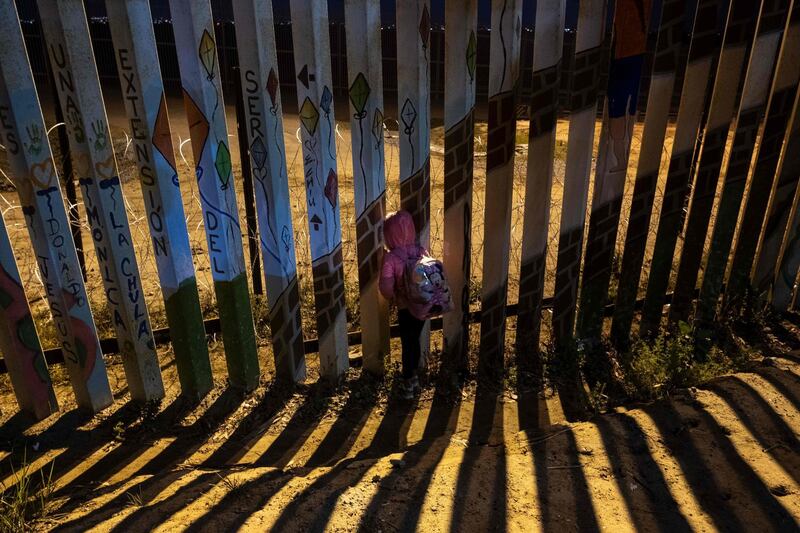 Britany Alondra, a seven year old migrant from Honduras, looks through the US-Mexico border fence in Playas de Tijuana, Mexico. AFP