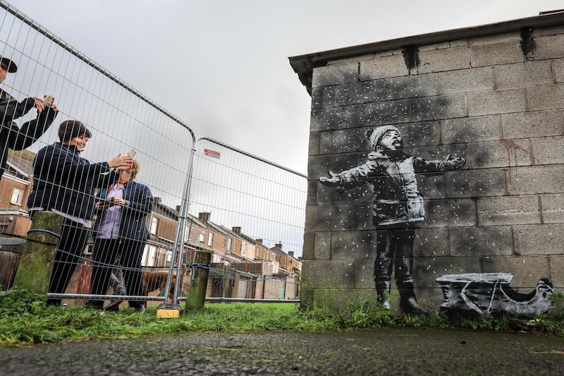 PORT TALBOT, WALES - DECEMBER 20: People gather around fences that have been erected to protect the latest  piece of artwork by the underground guerrilla artist Banksy on December 20, 2018 in Port Talbot, Wales. The British graffiti artist who keeps his identity a secret, confirmed yesterday that the artwork was his using his verified Instagram account to announce "Season's greetings" with a video of the artwork in Port Talbot. (Photo by Matt Cardy/Getty Images)
