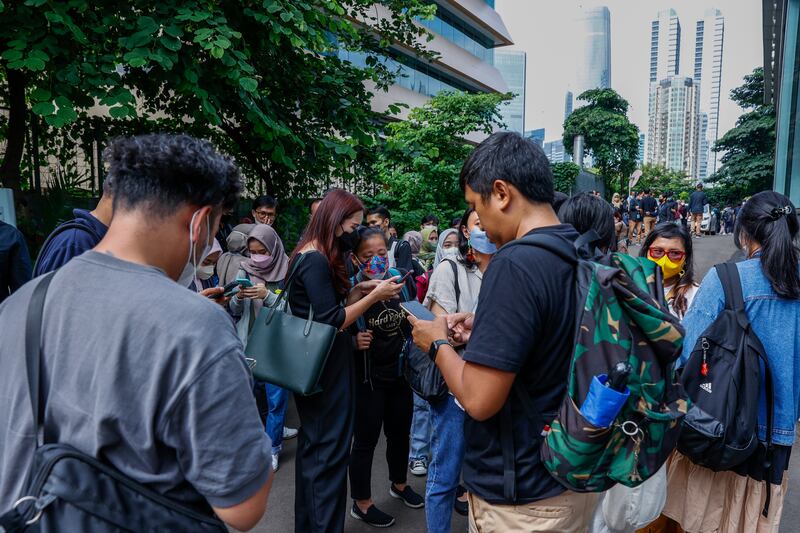 People check their phones for alerts after an earthquake shook a business area in Jakarta. EPA