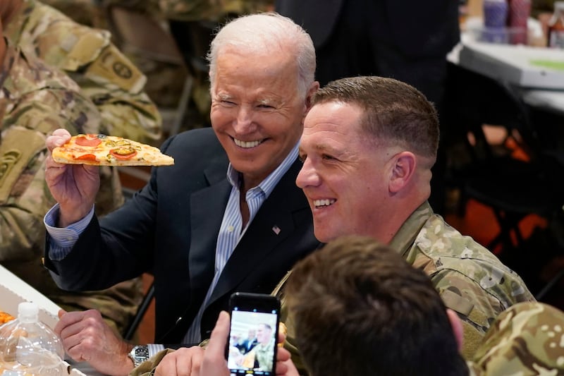 Mr Biden holds a slice of pizza during his meeting with US troops. AP