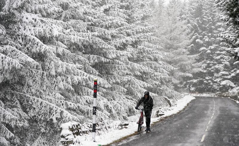 The UK was hit by low temperatures and spring snow on Wednesday and Thursday. Here a cyclist wheels his bike through snow in Allenheads, in the Pennines in Northumberland. PA
