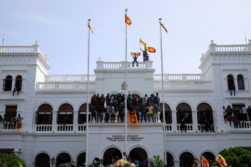 Protesters in Colombo hold Sri Lankan flags as they stand on top of the office of acting Prime Minister Ranil Wickremesinghe, amid the country's economic crisis. Reuters