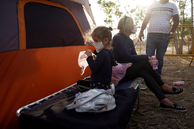 Yanisleydi de la Rosa, 34, and her daughter Anyeli cruz de la Rosa, 4, who are seeking asylum in the U.S. wear protective masks, amid an outbreak of coronavirus disease (COVID-19), in the migrant camp of Matamoros, Mexico. REUTERS