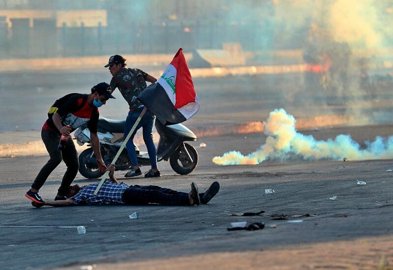 A protester falls injured while holding a national flag during a demonstration in Baghdad, Iraq. AP