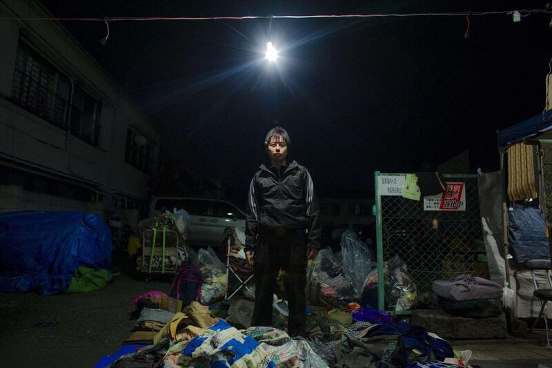 Trader Kazumoto Miyaoka poses in the pile of secondhand clothes and rags that he sells at Boroichi flea market in Tokyo. In the 16th century, Boroichi was a place for farmers to buy and sell rags, known as boro, for mending clothes and weaving sandals. Thomas Peter / Reuters