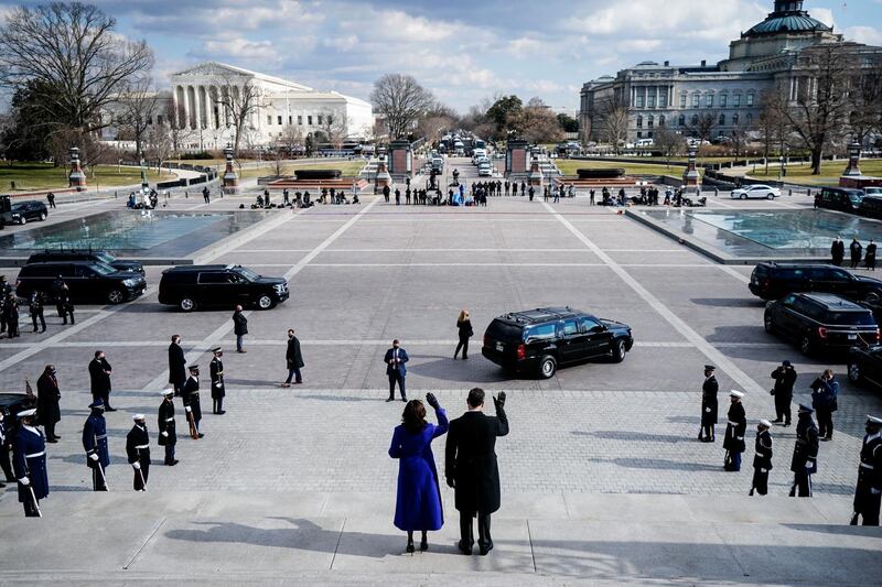 Vice President Kamala Harris and her husband Doug Emhoff, wave from the Capitol steps as former Vice President Mike Pence's motorcade departs. AP Photo