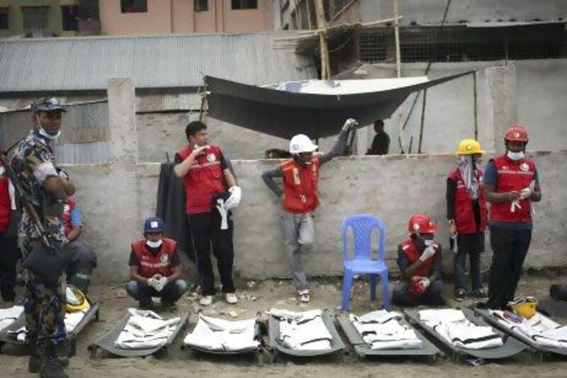 Health volunteers wait next to body bags as they prepare to extract more dead bodies from the garment factory building which collapsed in Savar, near Dhaka.