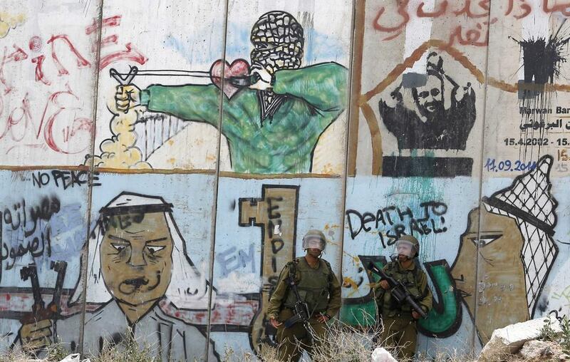 Israeli soldiers stand guard in front of a section of the controversial Israeli barrier during a protest by Palestinians in solidarity with prisoners on hunger strike, at Qalandia checkpoint near the West Bank city of Ramallah. Mohamad Torokman / Reuters