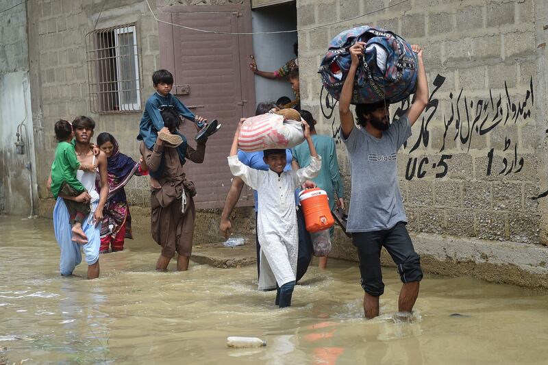 People carry their belongings through a flooded street. AFP