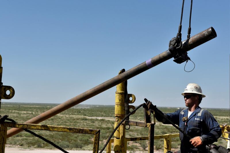 FILE PHOTO: A drilling crew member raises drill pipe onto the drilling rig floor on an oil rig in the Permian Basin near Wink, Texas U.S. August 22, 2018. REUTERS/Nick Oxford/File Photo