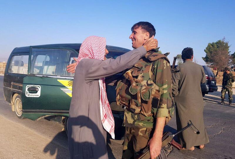 A man greets a Syrian army soldier in the town of Tel Tamer in northeast Syria. REUTERS