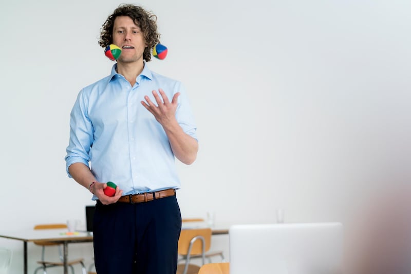 Smiling businessman juggling balls in his office. Getty Images