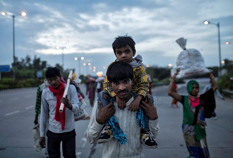 A migrant worker carries his son as they walk along a road with others to return to their village, during a 21-day nationwide lockdown to limit the spreading of coronavirus disease (COVID-19), in New Delhi, India, March 26, 2020. REUTERS/Danish Siddiqui     TPX IMAGES OF THE DAY