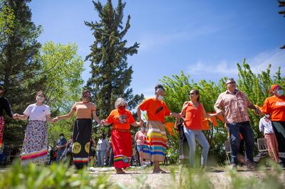 Attendees perform a round dance during a press conference and prayer vigil at the former Muscowequan Indian Residential School, one of the last residential schools to close its doors in Canada in 1997 and the last fully intact residential school still standing in Saskatchewan at Muskowekwan First Nation, Saskatchewan, Tuesday, June 1, 2021. The vigil was in response to the remains of 215 children recently found at the Kamloops Indian Residential School. (Kayle Neis/The Canadian Press via AP)