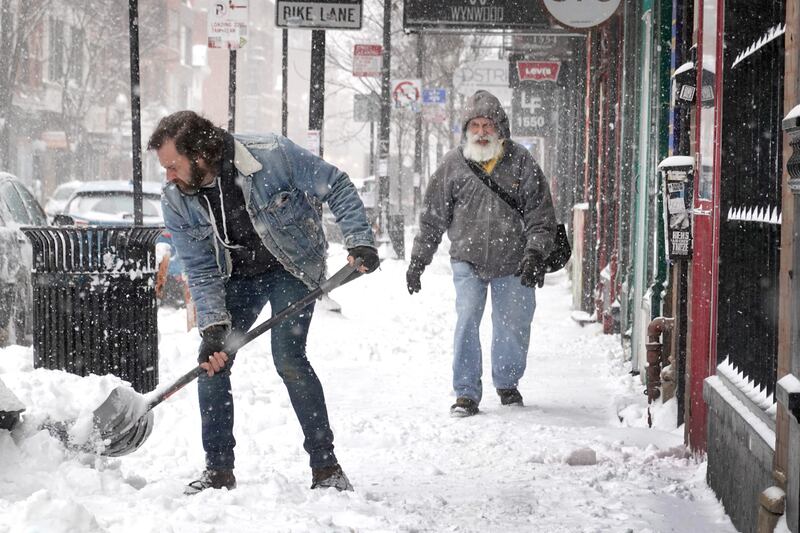 A worker clears snow from the front of a business in Chicago, Illinois. AFP