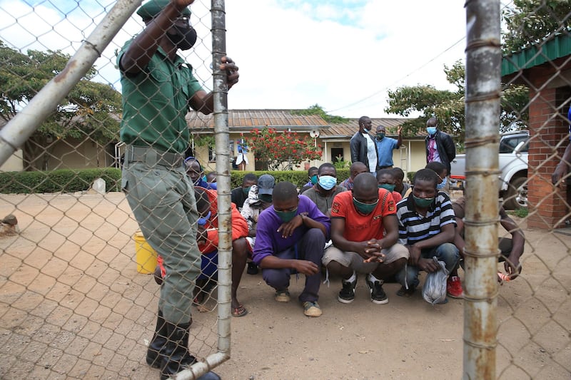 Prisoners kneel behind a gate before their release at Chikurubi Maximum Prison in Harare, Zimbabwe. Three thousand prisoners have been freed from prison to ease the pressure on the country's prisons in view of the pandemic. EPA