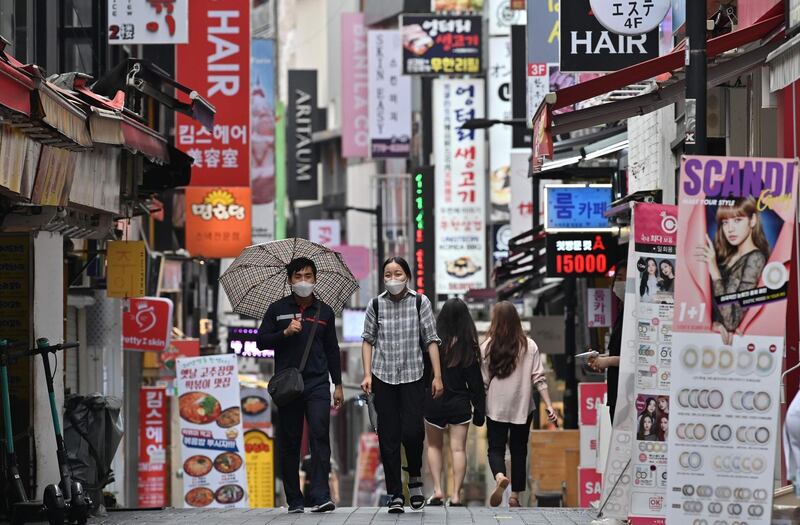 People walk through the Myeongdong shopping district in Seoul. South Korea's central bank slashed its growth forecast predicting the world's 12th-largest economy will shrink more than one percent this year as it braces for a surge of coronavirus infections.  AFP