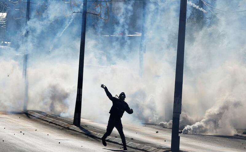 A Palestinian protester hurls stones as tear gas is fired by Israeli troops in Bethlehem. Mussa Qawasma / Reuters