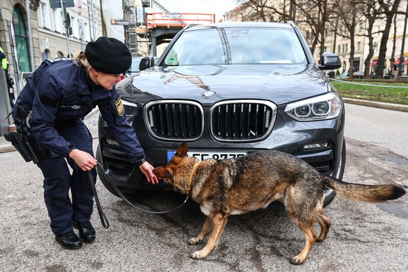 A sniffer dog checks a car for explosives in front of the conference venue. EPA