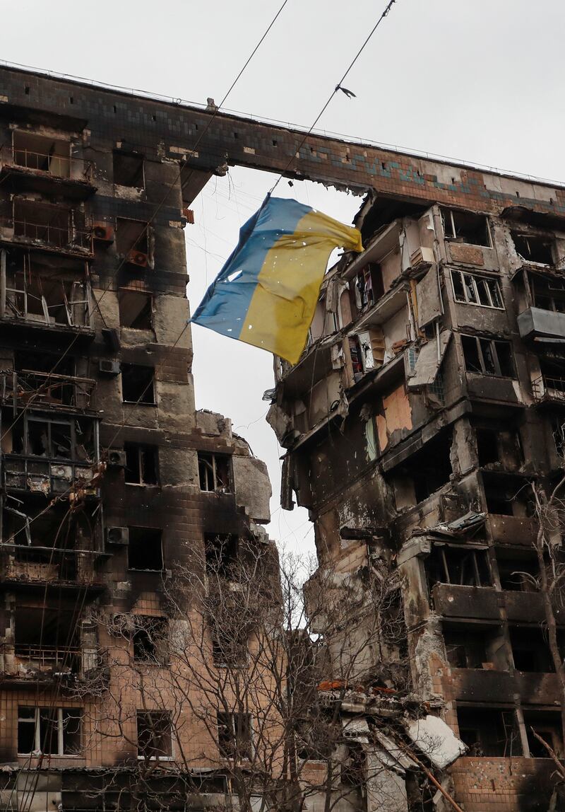 A torn Ukrainian flag in front of a ruined Mariupol apartment building. Reuters