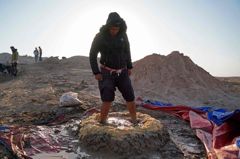 A worker mixes clay and wheat stalks to make traditional bricks during a German-Iraqi archaeological expedition.